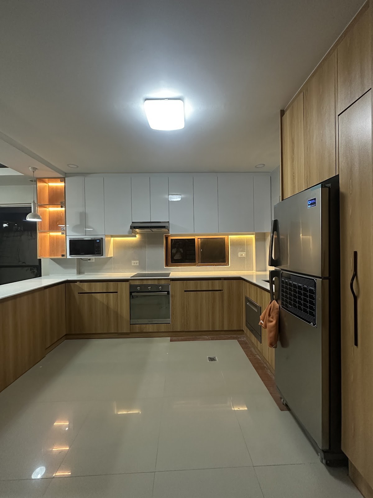 Modular kitchen in wood and white with under-cabinet lighting, built by MS Gabaldon in Quezon City